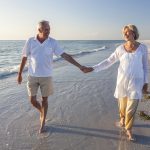 Happy Senior Couple Walking Holding Hands Tropical Beach